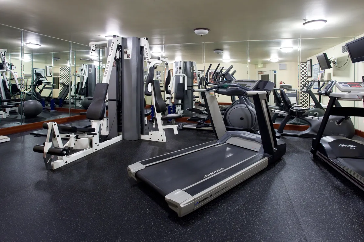 An interior fitness center outfitted with treadmills, weight machines, exercise balls, and mirrored walls. The space is bright, modern, and inviting, with ample room for individual or group workouts.