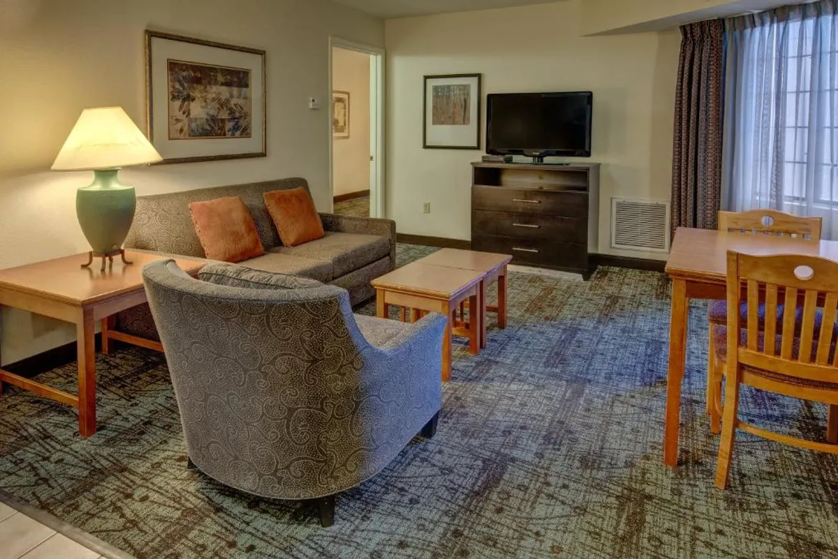 This image showcases a warm, inviting living space featuring a plush sofa, stylish armchair, sleek dining table, and a large television—perfect for relaxing, sharing meals, and spending quality time together. The ambiance is cozy and comfortable, ideal for unwinding after exploring Denver.